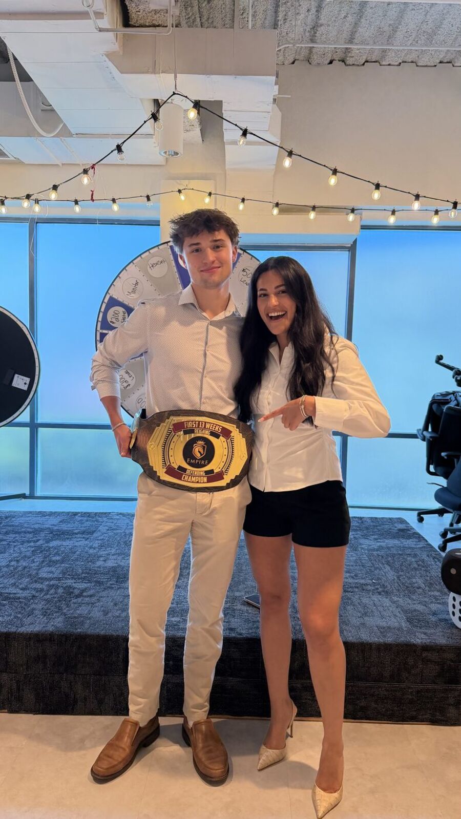Two team members holding a championship belt award