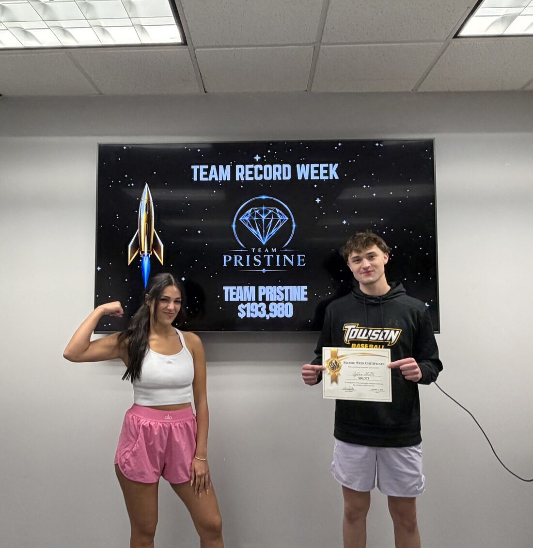 Team members celebrating Team Record Week in front of a Team Pristine screen
